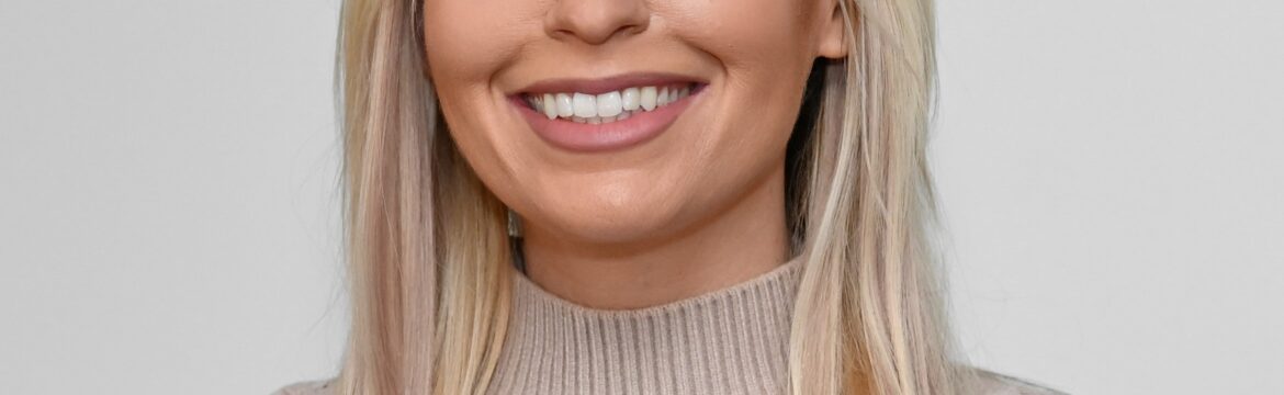 Aly Cromer headshot, wearing a beige turtleneck, white background