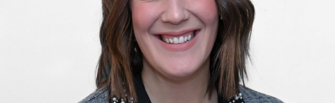 Monica Schafer headshot, wearing a black blouse and a grey plaid jacket