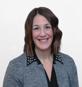 Monica Schafer headshot, wearing a black blouse and a grey plaid jacket