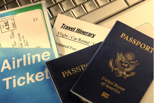 Group Personal Excess Insurance typically provides worldwide protection. Image of airline tickets, travel itinerary, passports, and laptop.