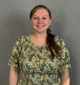 Headshot of Ciara Gottron, gray background and a green floral shirt