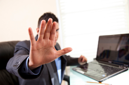 Employee Dishonesty Insurance - Picture of a male white collar employee blocking a camera from recording financial theft from his employer.