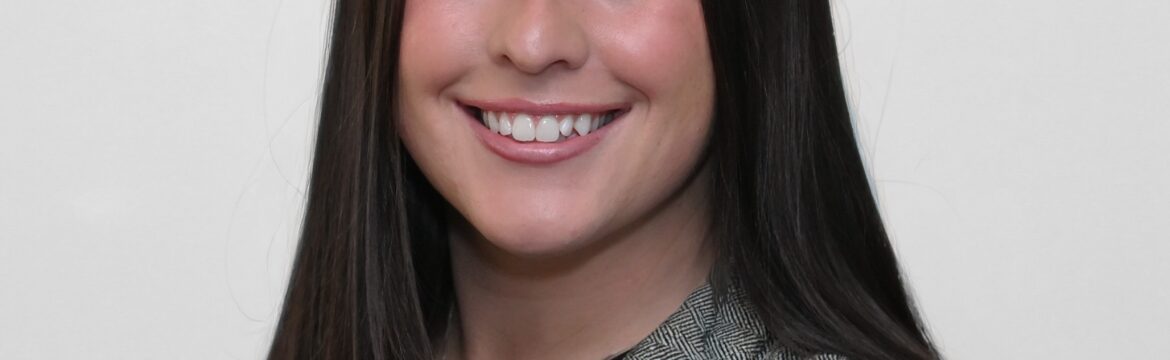 Samantha Palumbo headshot, wearing a black shirt and grey plaid jacket, white background