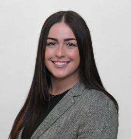 Samantha Palumbo headshot, wearing a black shirt and grey plaid jacket, white background