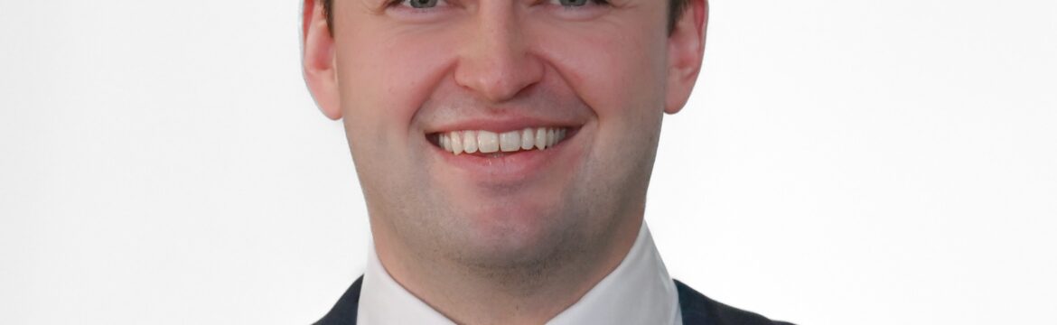 Levi McCrady headshot, white shirt yellow tie, and a blue plaid sport coat, white background