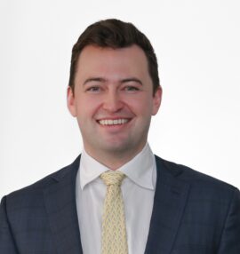 Levi McCrady headshot, white shirt yellow tie, and a blue plaid sport coat, white background