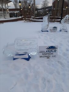 Close up of an ice sculpture of an old school car, next to it a sign that reads "Ligonier Ice Fest, Simpson & McCrady LLC"