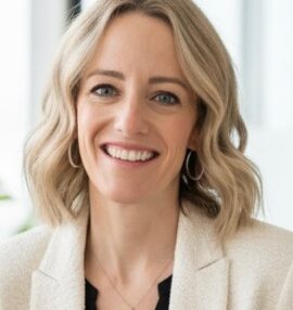 Jessica's headshot. Wearing a black blouse with a cream blazer.